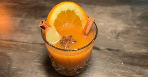 A pumpkin, orange, bourbon cocktail garnished with fruit and spices