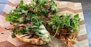 prosciutto arugula pizza on a cutting board