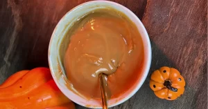 Dulce de leche in a grey bowl with a shiny spoon