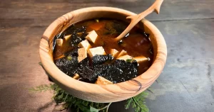 Miso soup in a wooden bowl with a wooden spoon