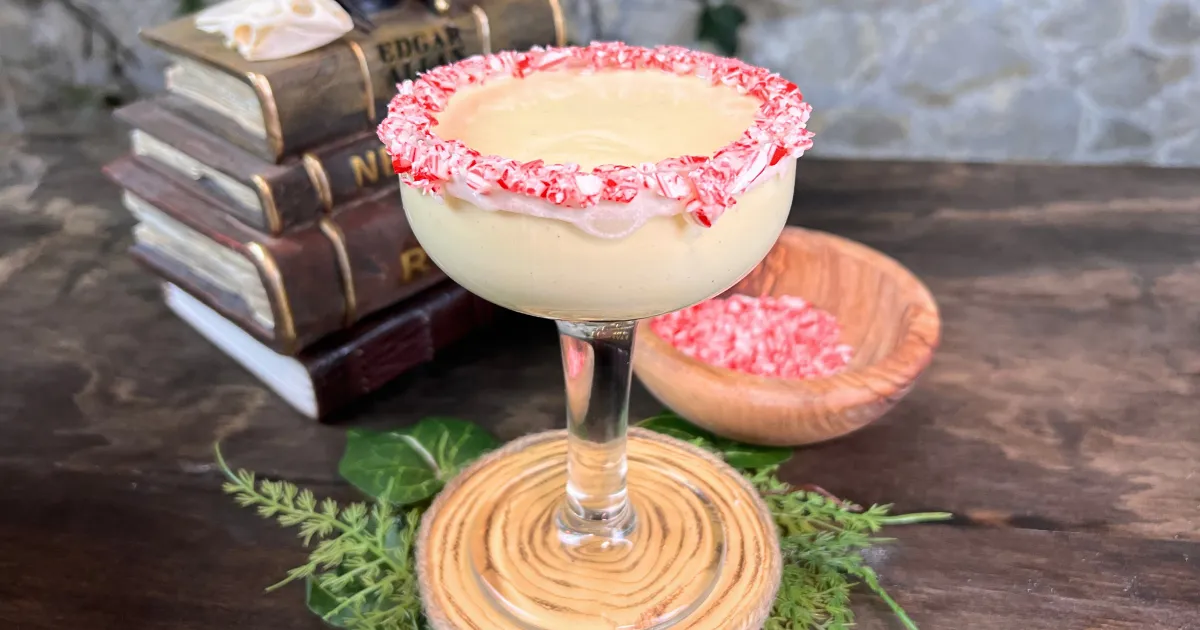 Frostmaiden's Midwinter Peppermint Eggnog in a tall glass with a peppermint and white chocolate rim