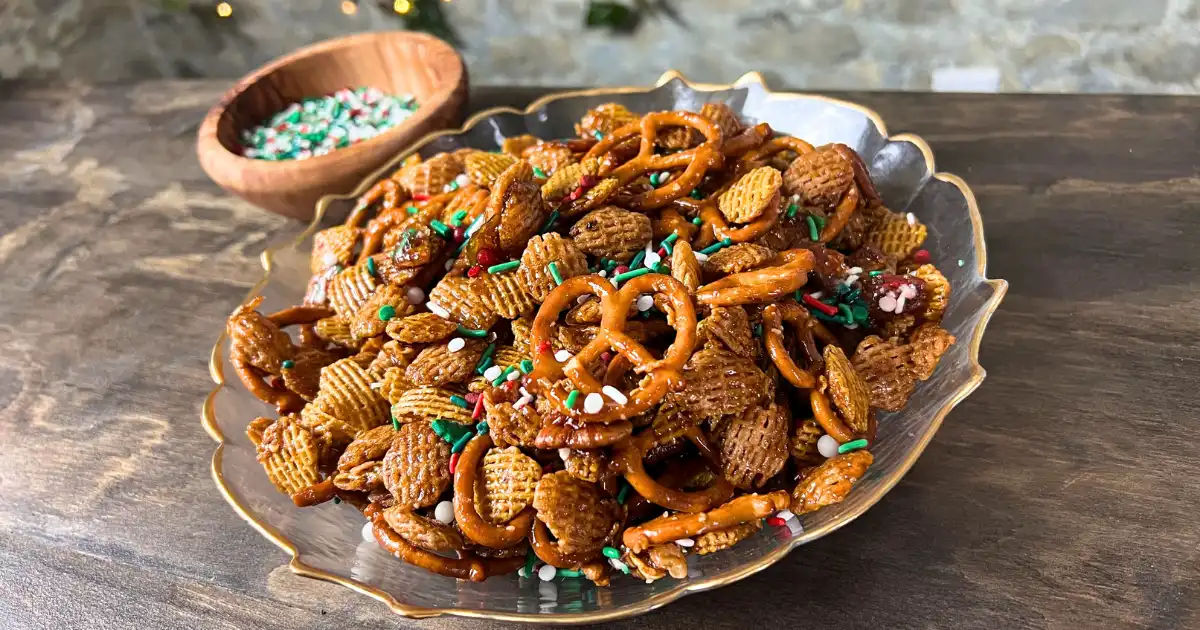 A caramelized snack with cereal, pretzels, nuts, and sprinkles in a glass bowl