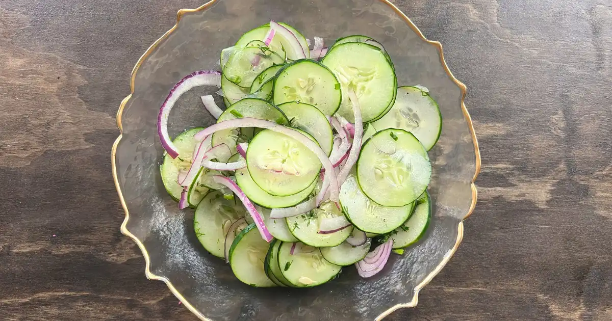 Cucumber salad in a glass bowl, topped with black pepper