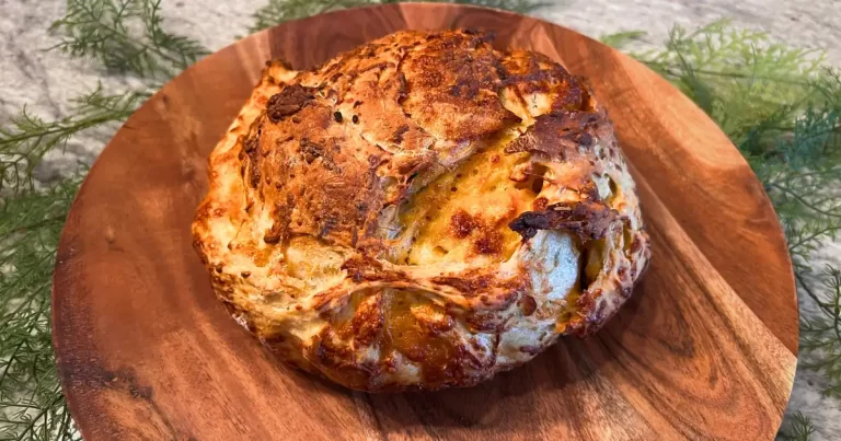 A crusty loaf of cheesy garlic bread on a wooden plate