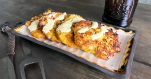 Fried squash patties on a plate with garlic aoli drizzled on top