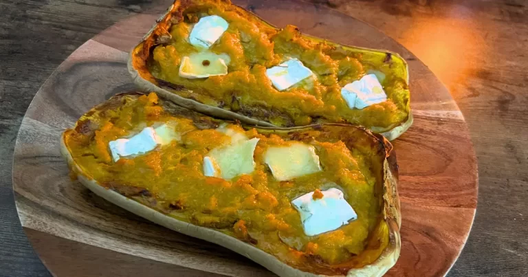 Two baked squash halves on a plate, topped with melted brie