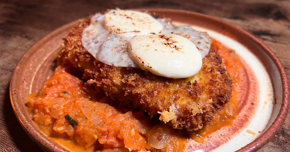 Chicken Parmesan topped with cheese, sitting on top of red tomato sauce